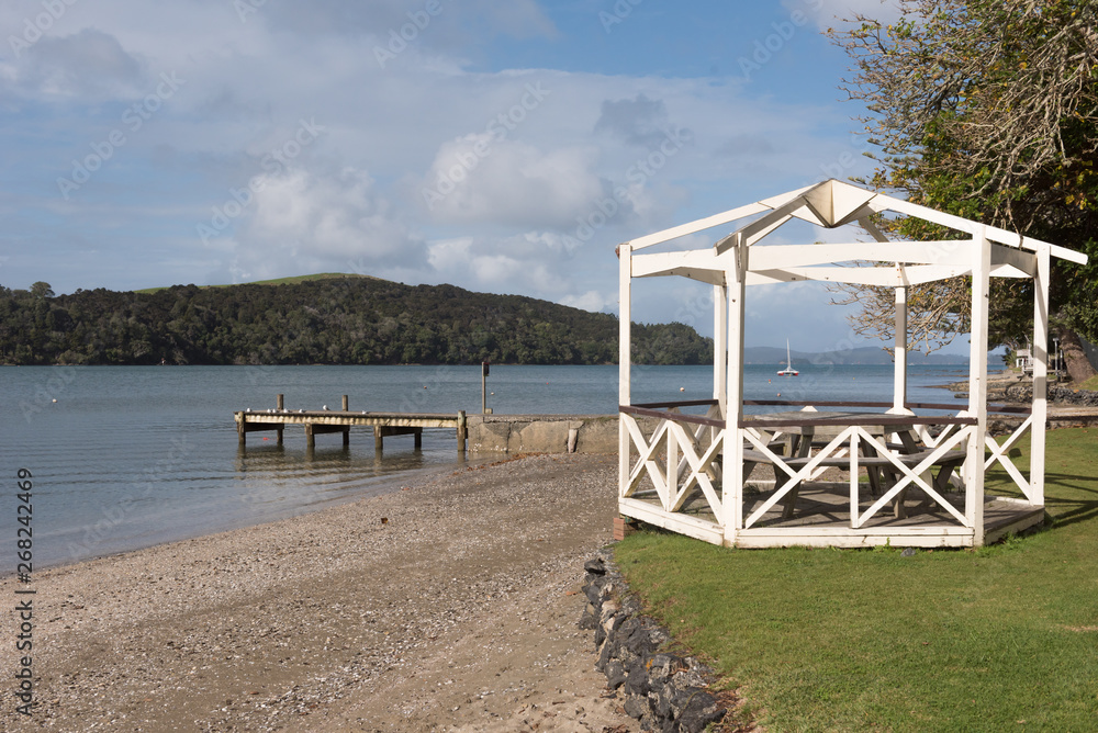 A gazebo on the foreshore of Sandspit with a small pier or jetty behind.  Auckland, New Zealand. Stock Photo