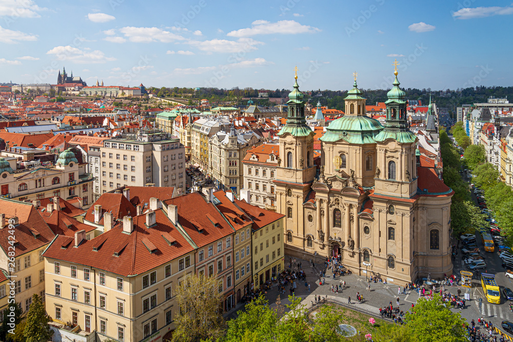 Outdoor sunny top aerial scenery of rooftop in old town and St. Nicholas' Church, Vltava River, and background Prague Castle and St. Vitus Cathedral on the hill in Prague, Czech Republic.