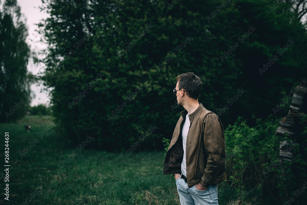 trendy A man in a brown leather jacket and in steampunk glasses in the forest.