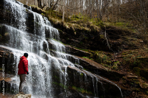 Guy in red jacket looks at waterfall