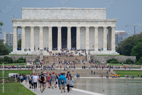 Washington DC: Crowds of hundreds of tourists walk along the reflecting pool of the National Mall toward the Lincoln Memorial monument