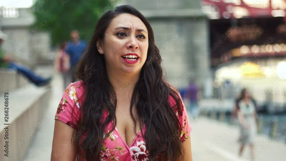 Young Latina woman talking head is at Chicago River Walk having an exciting conversation and happy showing many facial expression while moving hair. wearing pink blouse Young Latina woman talking head is at Chicago River Walk having an exciting conversation and happy showing many facial expression while moving hair. wearing pink blouse