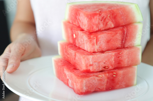 Hand holding ceramic white plate with watermelon slice concept. Watermelon is healthy fruit for summer and diet food