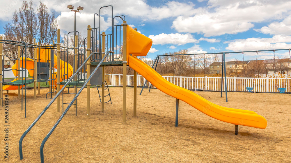 Panorama Playground with slides and swings under the blue sky filled with puffy clouds