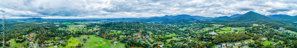 Ultra wide aerial panorama of scenic rural landscape with houses surrounded by trees, grasslands, and mountains. Ultra wide aerial panorama of scenic rural landscape with houses surrounded by trees, grasslands, and mountains.