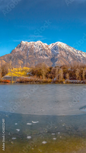 Clear Vertical Scenic panorama of a lake against snow capped mountain and blue sky in winter