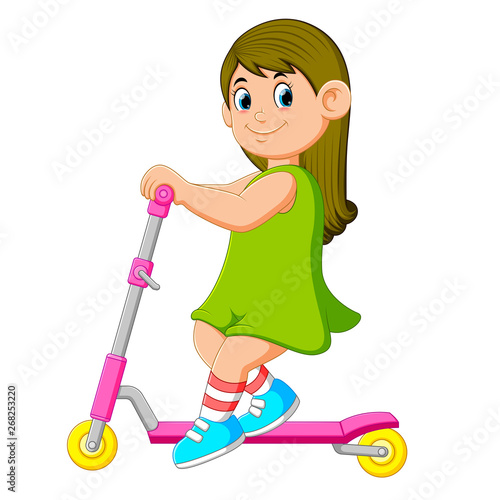 the girl with the green dress is playing on the scooter