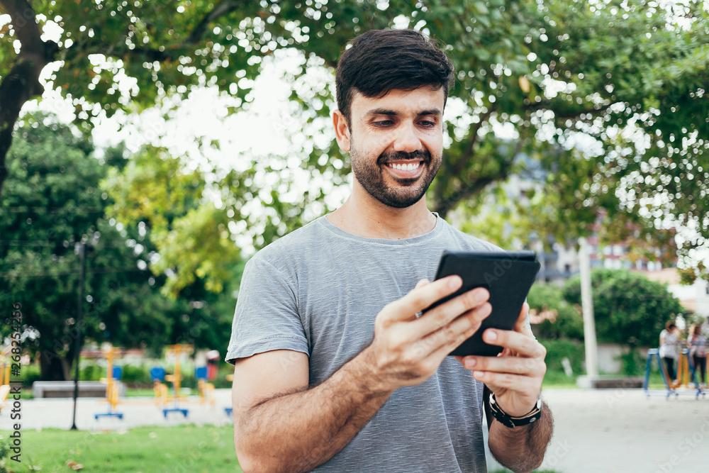 Young man reading e-book in the park