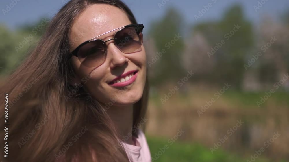 SLOW MOTION 120fps: Young happy traveler brown haired woman girl smiling and turning around in a new destination country with a pink sakura cherry blossom trees in Baltic states - Flying hair SLOW MOTION 120fps: Young happy traveler brown haired woman girl smiling and turning around in a new destination country with a pink sakura cherry blossom trees in Baltic states - Flying hair