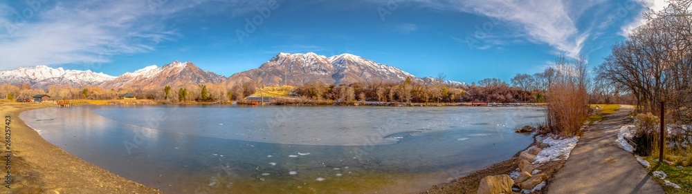 Scenic panorama of a lake against snow capped mountain and blue sky in winter