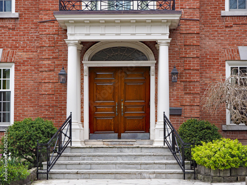 elegant double wooden front door of large suburban house with portico photo