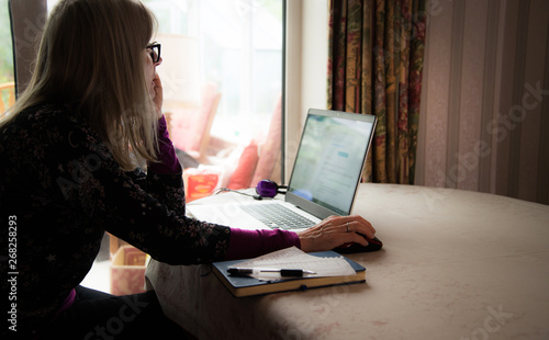 Freelance finance secratary watching webinar on her laptop,wearing headphones photo