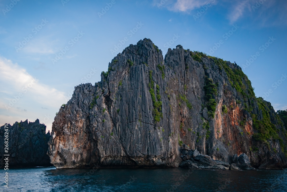 Limestone cliffs at sunset with orange leaks off Miniloc Island in El nido region of Palawan in the Philippines. Limestone cliffs at sunset with orange leaks off Miniloc Island in El nido region of Palawan in the Philippines.