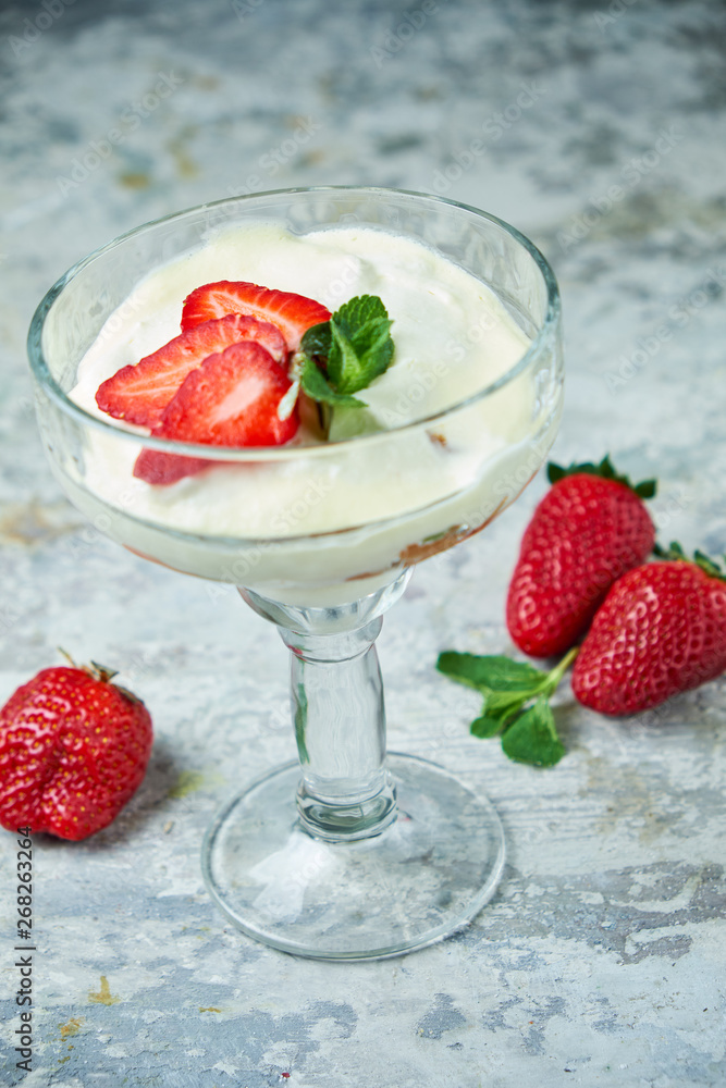 Ice cream with strawberries in a glass vase. Gray textured background. Dessert Ice cream with strawberries in a glass vase. Gray textured background. Dessert