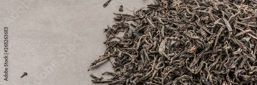 Dried tea is poured scattered on a grey textured background.
