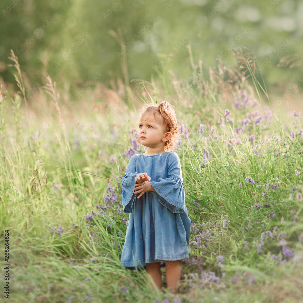 Little girl stands in field and looks away with a serious look Little girl stands in field and looks away with a serious look