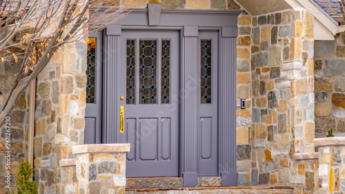 Panorama Facade of a home with a beautiful stone wall and gray front door photo