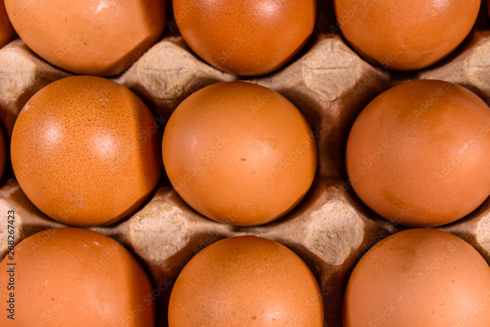 Pile of the hen eggs in paper tray on wooden table. Top view Pile of the hen eggs in paper tray on wooden table. Top view