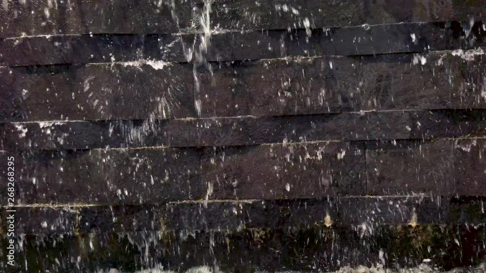 Moving shot of water flowing from upper floor to the ground with brick wall as a background Moving shot of water flowing from upper floor to the ground with brick wall as a background