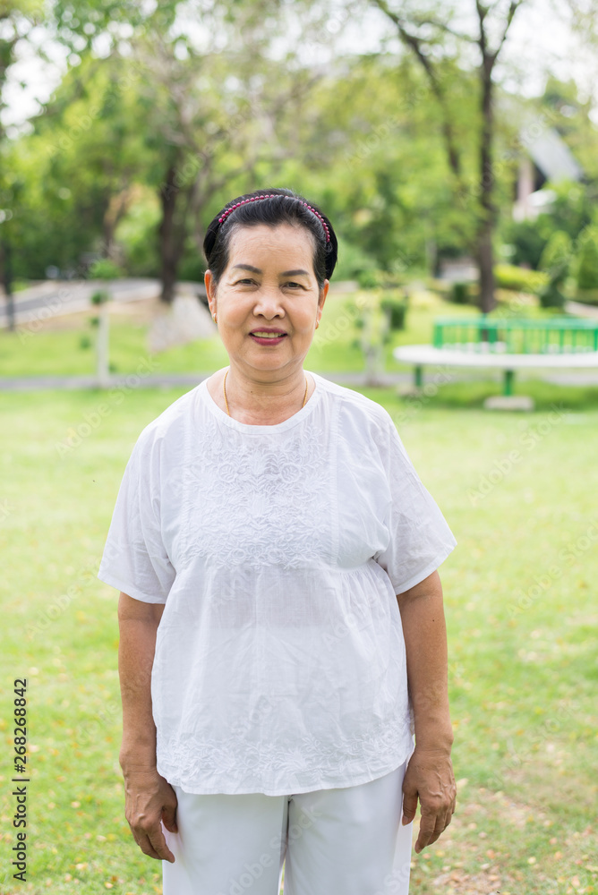 Pictureof a elderly asian female standing at garden,Happy and smiling Pictureof a elderly asian female standing at garden,Happy and smiling