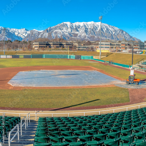 Square Baseball field with green tiered seating against mountain and vibrant blue sky