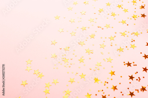 Gold star shape confetti on pink background.