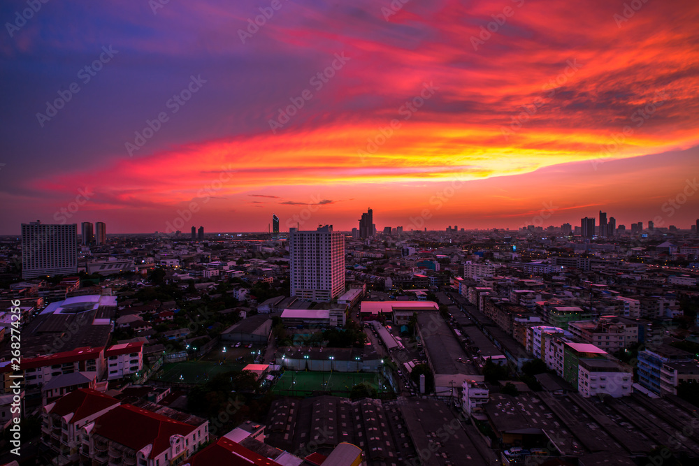 Fototapeta premium Panorama background of city views, with colorful twilight sky, high-rise buildings (condominiums, offices, expressways) and blurred lights from roads and traffic.