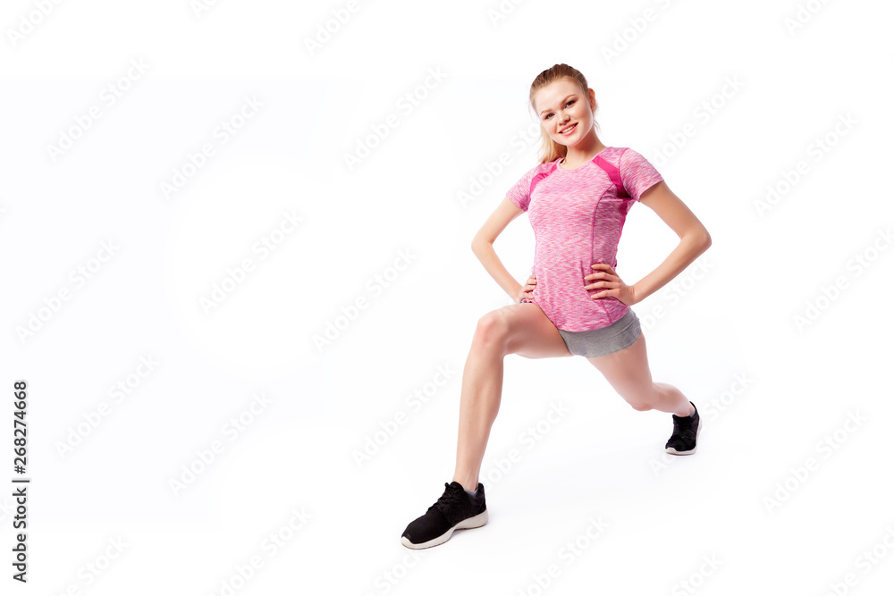 Young woman in sports clothes  makes and stretch  legs, doing exercise tilts, legs wide apart on white isolated background. Side view.Fit girl living an active lifestyle