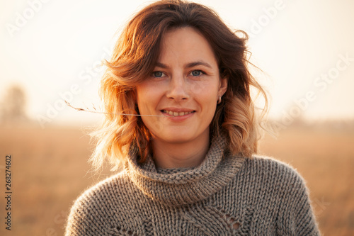 Portrait joyful young woman brunette in brown knit sweater made of natural wool and jeans having fun, smile and enjoy day on field. stylish hipster woman