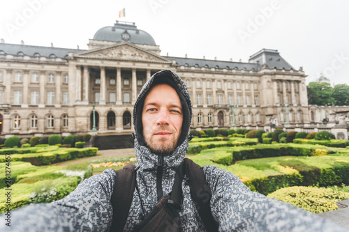 Male tourist takes selfie picture against the backdrop of the Royal Palace in Brussels, Belgium