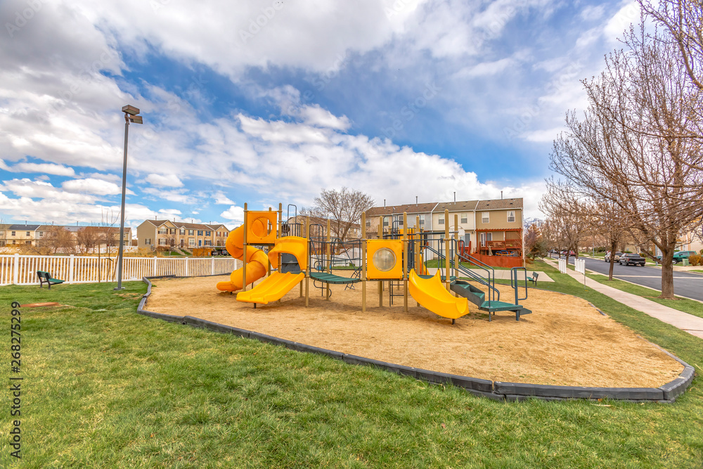 Colorful slides at a playground with homes and cloudy sky in the background Colorful slides at a playground with homes and cloudy sky in the background