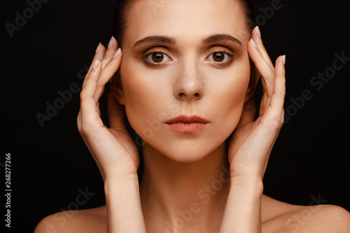 Fotografía Portrait of a beautiful woman with collected hair and bare shoulders on a black