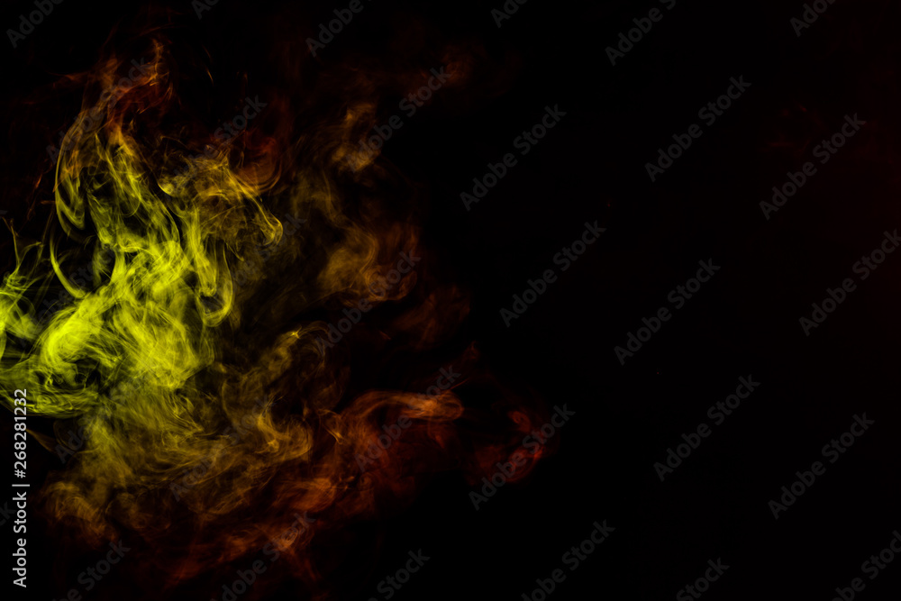 Beautiful horizontal column of smoke in the neon bright light of red, green, yellow and orange on a black background exhaled out of the vape. Nice pattern for printing and backdrop of colored waves.
