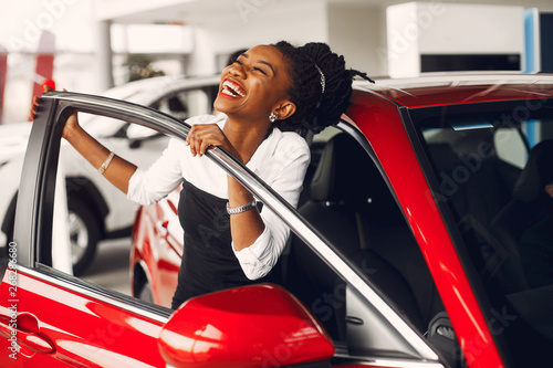 Woman buying the car. Lady in a car salon. Elegant black girl