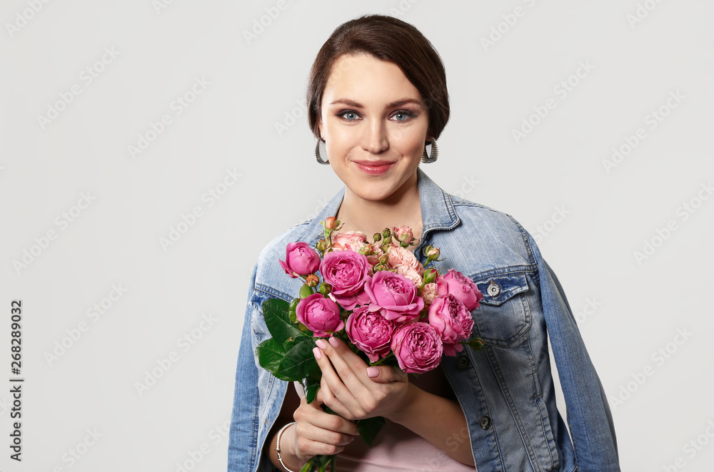 Beautiful young woman with bouquet of flowers on light background Beautiful young woman with bouquet of flowers on light background