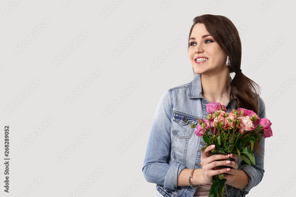 Beautiful young woman with bouquet of flowers on light background Beautiful young woman with bouquet of flowers on light background