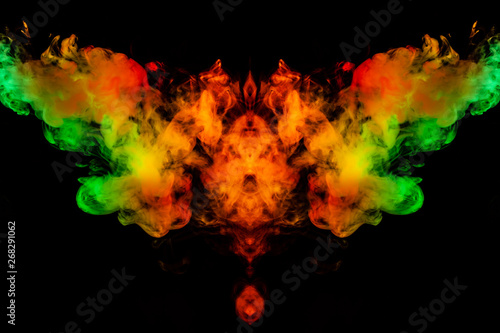 Smoke of different green, yellow, orange and red colors in the form of horror in the shape of the head, face and eye with wings on a black isolated background. Soul and ghost in mystical symbol © Aleksandr Kondratov
