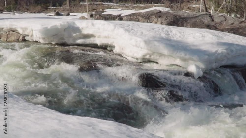 old stone bridge in etnedal arches over snow covered riverbank in spring melt slowmotion 100fps photo