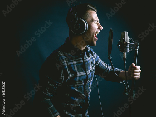 The young guy sings in recording studio