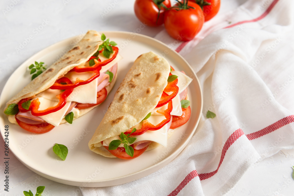 Piadina romagnola - Italian flatbread with prosciutto, tomato, basil, pepper and cheese on white background. Close up. Copy space Piadina romagnola - Italian flatbread with prosciutto, tomato, basil, pepper and cheese on white background. Close up. Copy space
