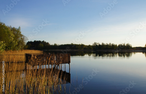 Fototapeta Naklejka Na Ścianę i Meble -  Old wooden arbor jetty on the lake at sunset.