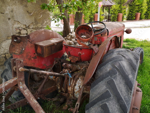 Ausrangierter alter Traktor in Rot mit Rost und Patina für die Landwirtschaft im Sommer bei Sonnenschein in der Altstadt von Alacati bei Cesme in der Provinz Izmir am Ägäischen Meer in der Türkei photo