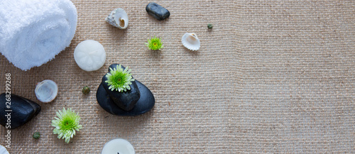 Spa setting with white flowers , stones and towel on a cloth background.