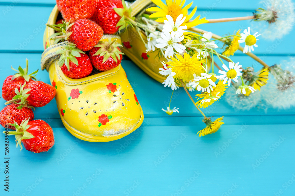 Summer background with strawberries, flowers and tiny baby shoes