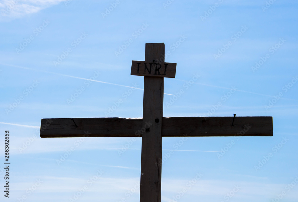 Wooden cross in silhouette on background of blue sky