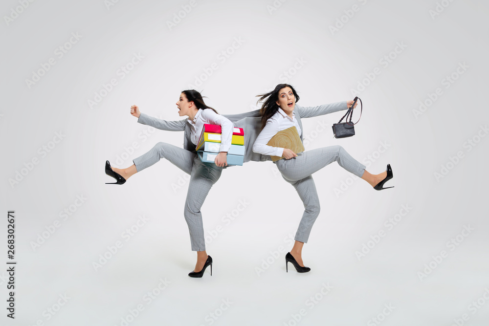 Young woman torning between cases and trying to do everything - holding folders and laptop on the run in different directions. Concept of office worker's troubles, business, problems, stress.