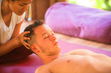 young beautiful and exotic Asian Thai therapist woman giving traditional head and facial Balinese massage to Caucasian man at alternative medicine healing spa