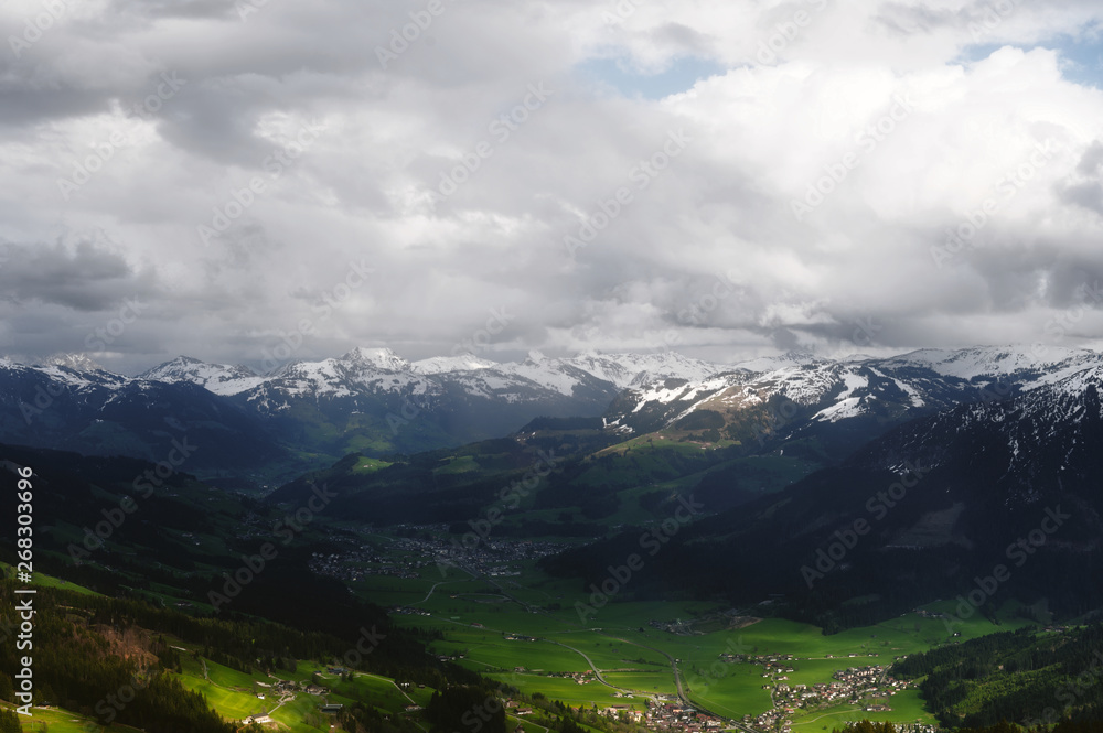 view in a valley from a mountain in the alps on a cloudly and dark day