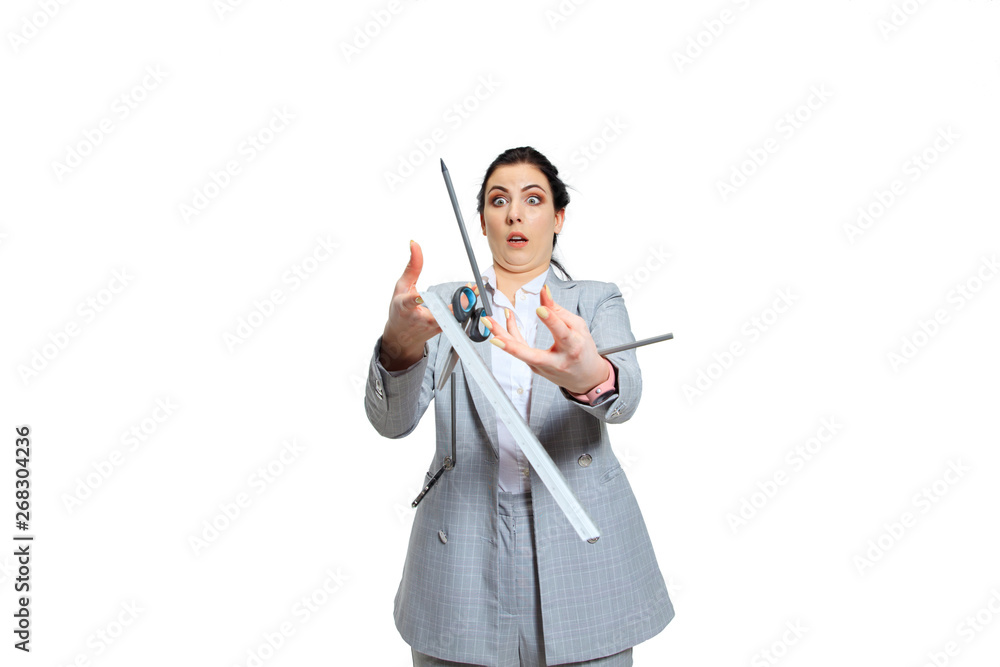 Young woman in grey suit losing concentration. Everything goes wrong and falls out of the hands, she's trying to catch that. Concept of office worker's troubles, business, problems and stress. Young woman in grey suit losing concentration. Everything goes wrong and falls out of the hands, she's trying to catch that. Concept of office worker's troubles, business, problems and stress.