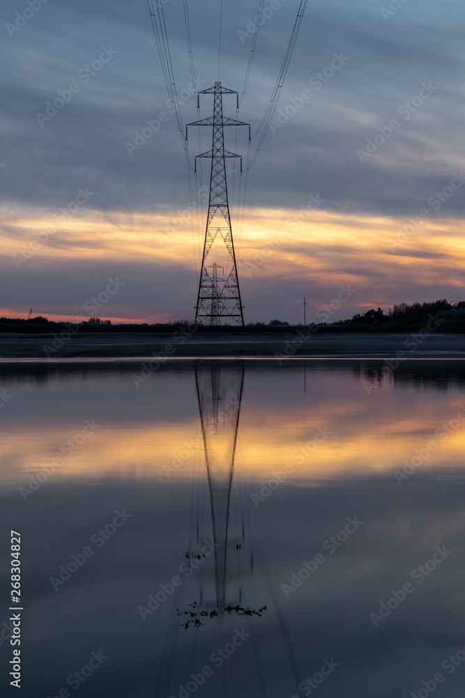 Pylon reflection in after sunset on the Loughor estuary, Llanelli, South Wales, UK